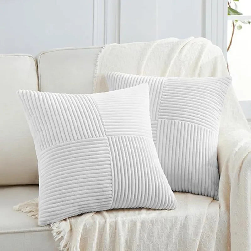 A set of two white retro corduroy patchwork throw pillow covers displayed on a light-colored sofa.