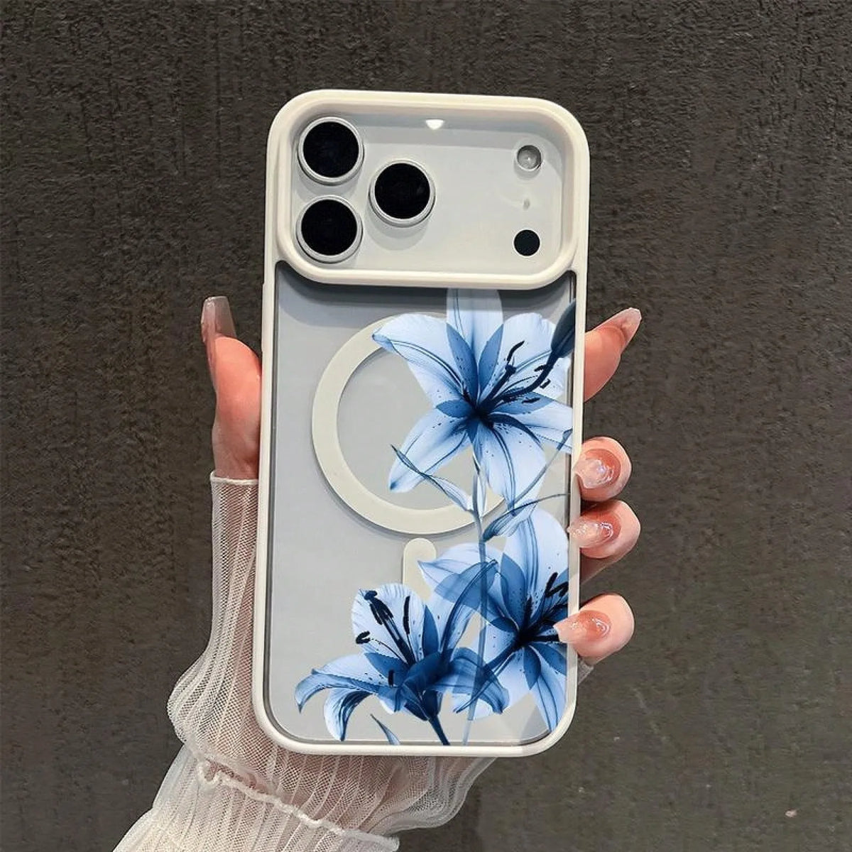 A hand holds a clear phone case featuring a blue lily floral design against a light background.