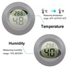 A small digital device displaying temperature and humidity readings on a round, gray casing.