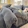 A gray velvet bedding set featuring a duvet cover and pillows on a bed.