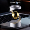 Silver and gold magnetic levitating spinning top resting on a laptop keyboard.