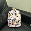 A pink and white Minnie Mouse themed backpack with a cow print pattern resting on a black leather surface.