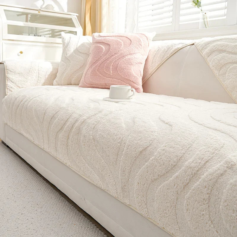 Funda de cojín de sofá texturizada color crema con un cojín de acento rosa y una taza blanca sobre una cama de color claro.