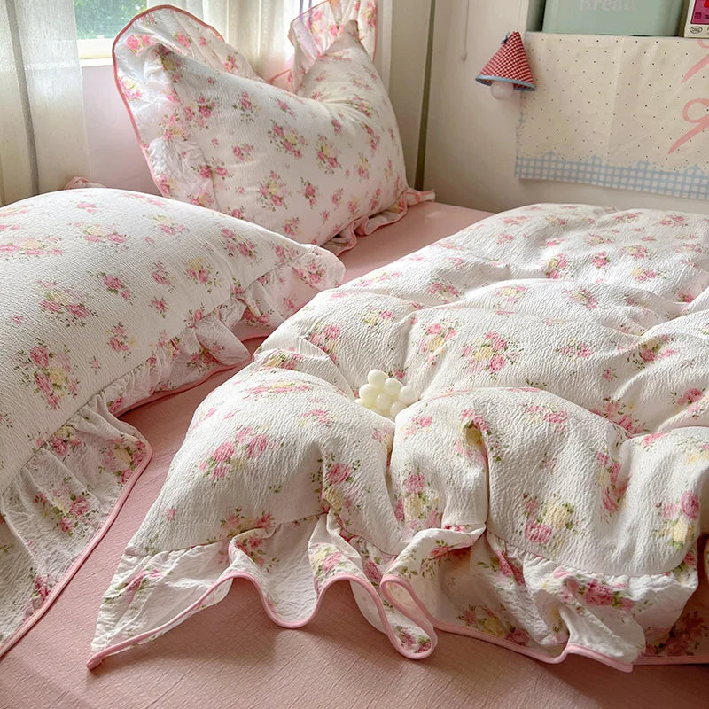 A floral duvet cover set in white with pink accents is displayed on a bed.