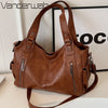 A brown vintage leather tote bag with multiple zippered pockets is displayed on a white surface.