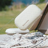 A white Naturehike foam inflatable camping pillow resting on a tan mat outdoors.