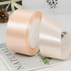 A roll of pale pink satin ribbon used for gift wrapping or DIY crafts.