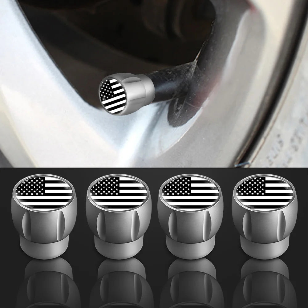 A set of four silver tire valve caps featuring an American flag design, shown in close-up against a metallic surface.