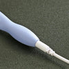 A close-up view of a light purple and white rechargeable LED crochet hook set with interchangeable heads on a dark surface.