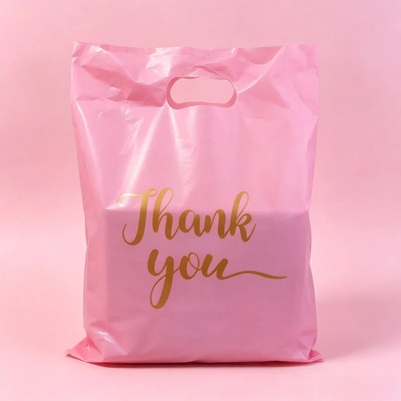 A pink gift bag with gold script text that reads Thank you