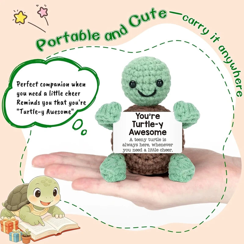A handmade crochet turtle doll with a positive message card is held in a person's hand.