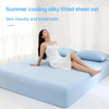 A woman is lying on a light blue bed with a white fitted sheet, demonstrating the silky and breathable fabric.