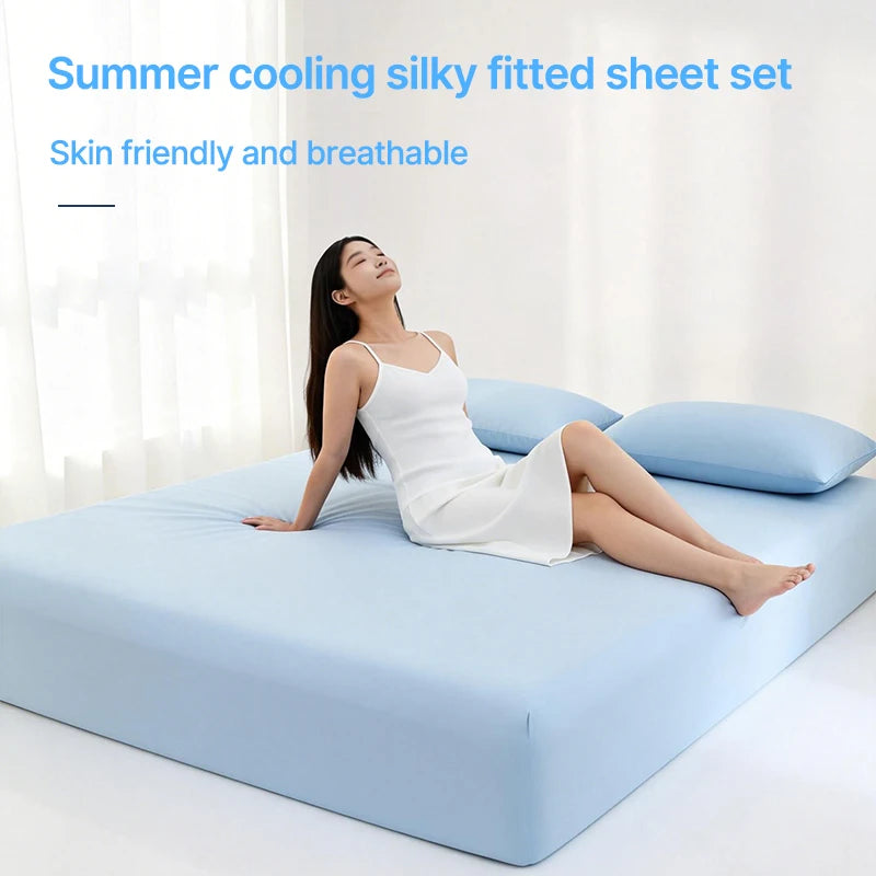 A woman is lying on a light blue bed with a white fitted sheet, demonstrating the silky and breathable fabric.