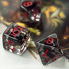 A close-up of several dark resin dice with red numbers scattered on a light surface.