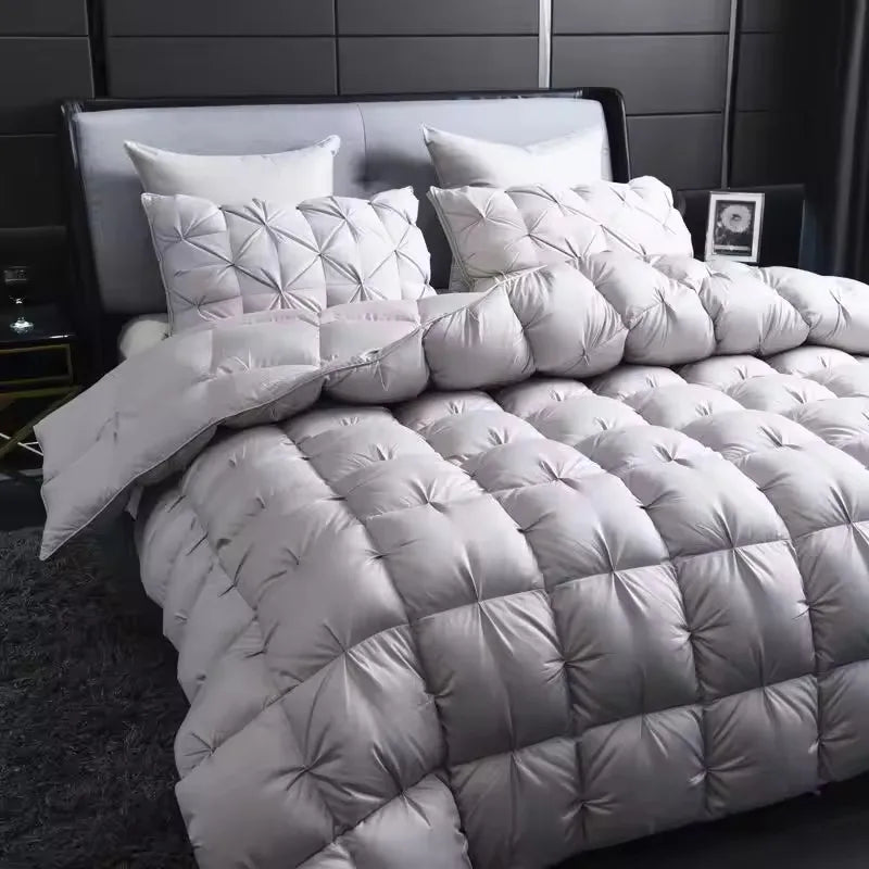 A white quilted comforter with a diamond pattern is displayed on a bed.