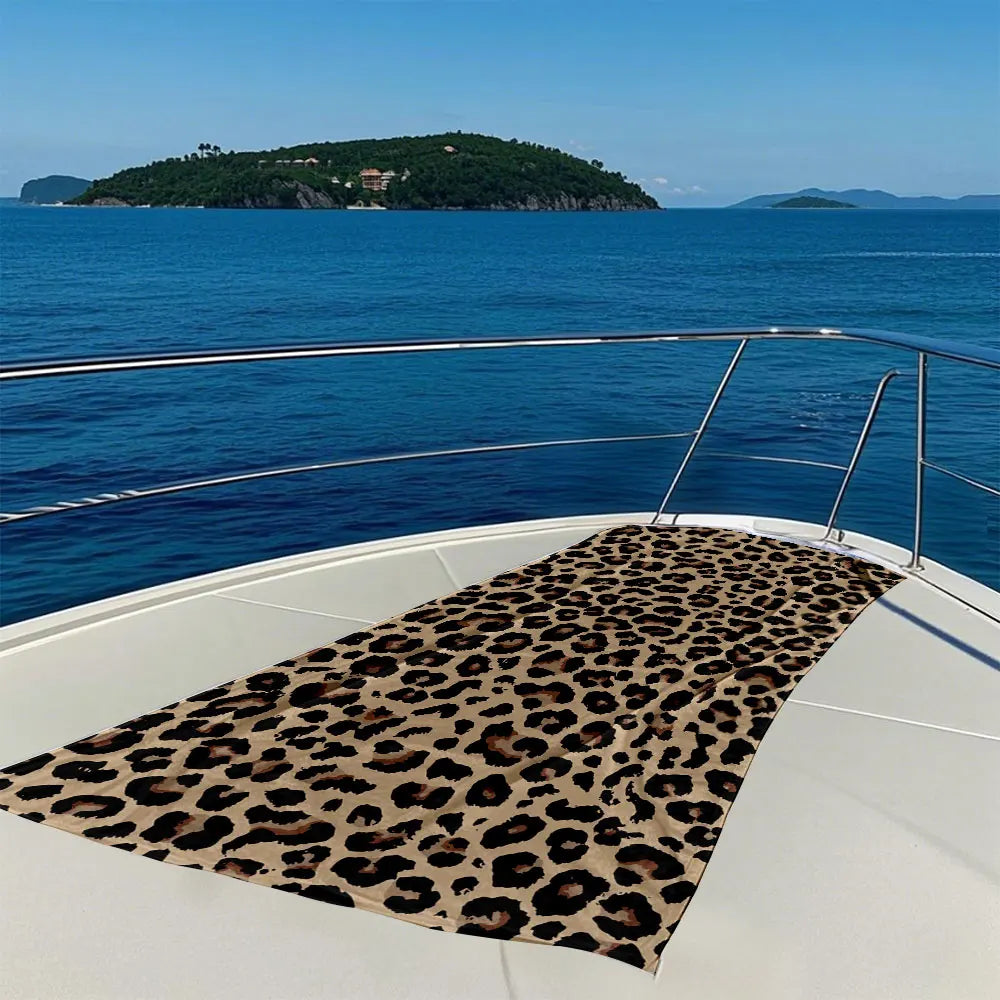 A leopard print towel laid out on the deck of a boat overlooking the sea and a distant island.