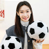 A woman holds a black and white football figurine against a gray cardigan.