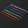 A collection of twenty large eye tapestry needles with curved tips in various colors laid on a dark surface.