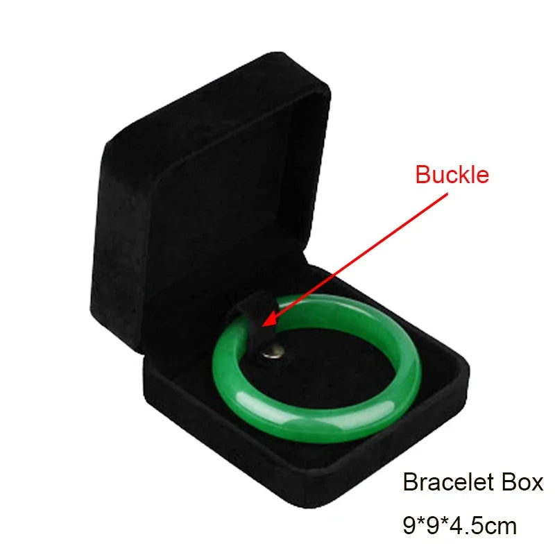 A black velvet bracelet box containing a green bangle with a buckle.