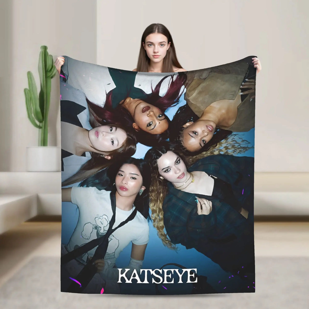A dark-themed blanket featuring a collage of female faces and the text KATSEYE