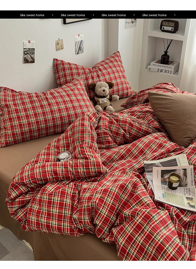A close-up of a red and green plaid duvet cover set displayed on a bed with pillows and a teddy bear.