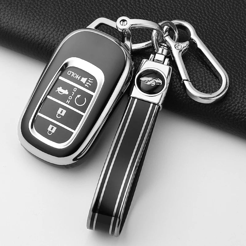 A black Honda key fob cover with a silver keychain attached, resting on a dark surface.