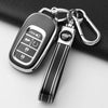 A black Honda key fob cover with a silver keychain attached, resting on a dark surface.