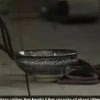 A handcrafted ceramic gourd wine set with a net bag resting on a surface.
