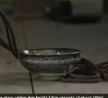 A handcrafted ceramic gourd wine set with a net bag resting on a surface.