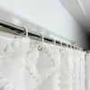 White boho waterproof shower curtain with tassels hanging on a metal rod