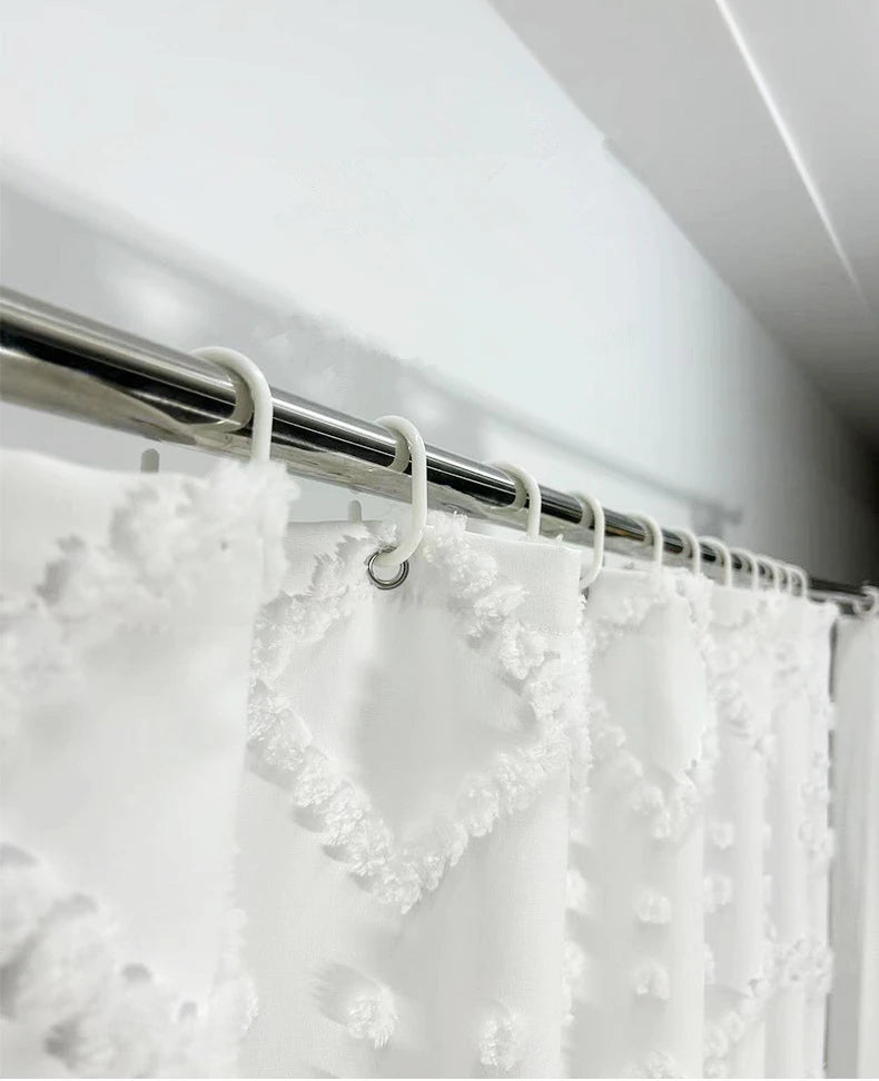 White boho waterproof shower curtain with tassels hanging on a metal rod