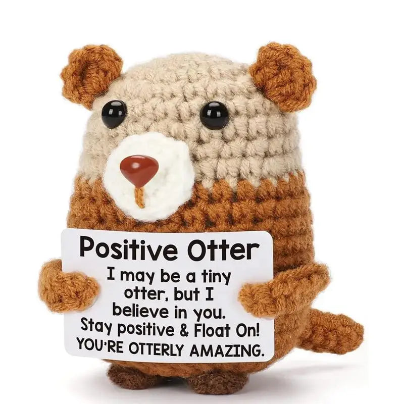 A handmade crochet otter doll with a positive message card that reads I may be a tiny otter but I believe in you.