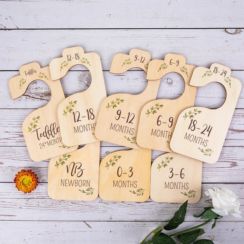 A set of wooden baby closet dividers used to organize clothing by size and age from newborn to 24 months.