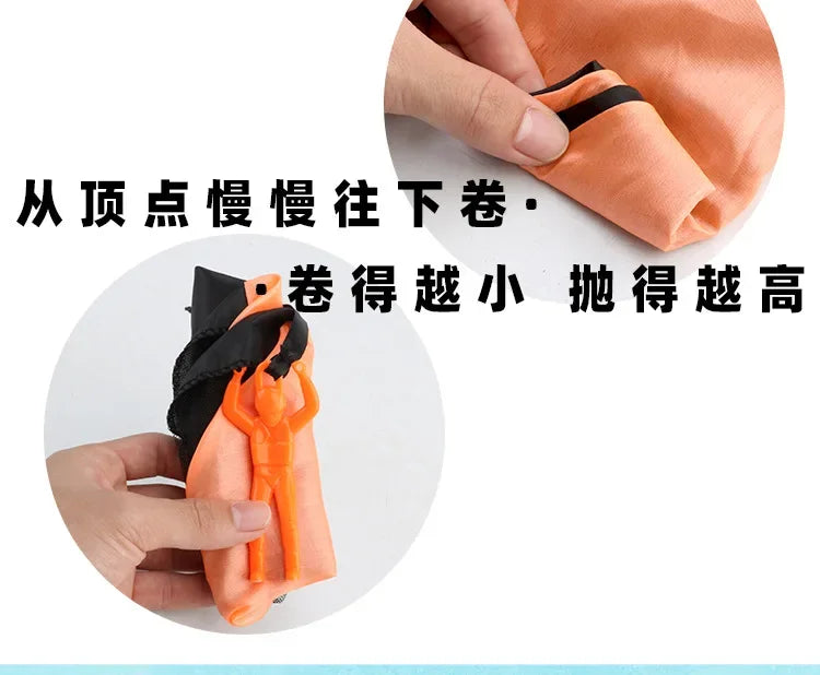 An orange hand-throw parachute toy with a mini soldier is being held by a hand.
