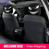 A set of two black car headrest covers featuring menacing evil grin designs installed in a vehicle interior.