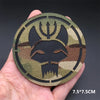 A round tactical patch featuring a stylized animal head design in olive green and black camouflage pattern.