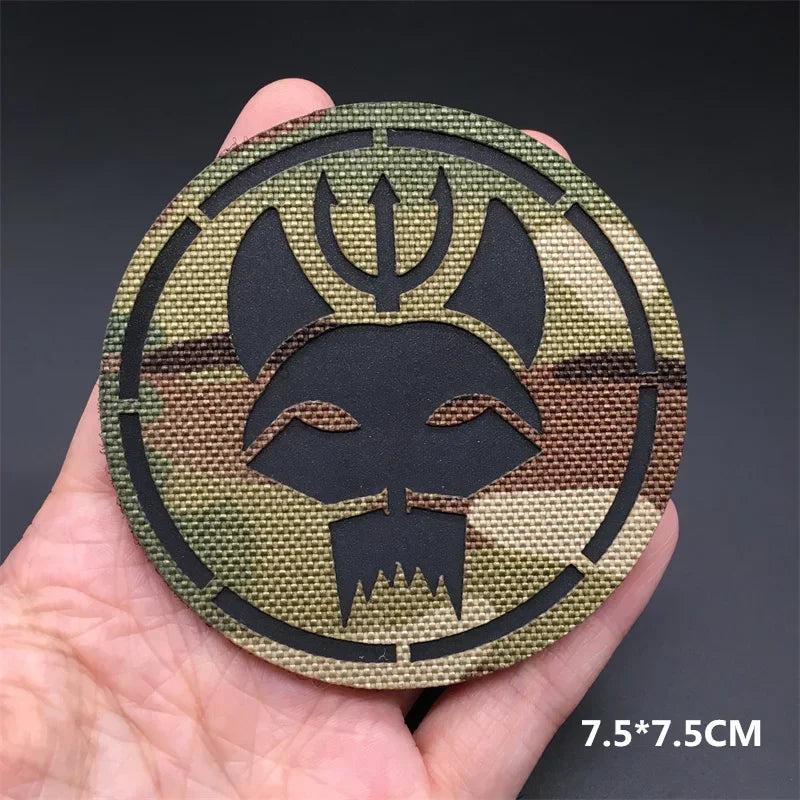 A round tactical patch featuring a stylized animal head design in olive green and black camouflage pattern.