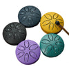 Six mini steel tongue drums in various colors including black, yellow, purple, and teal, arranged around a central mallet.