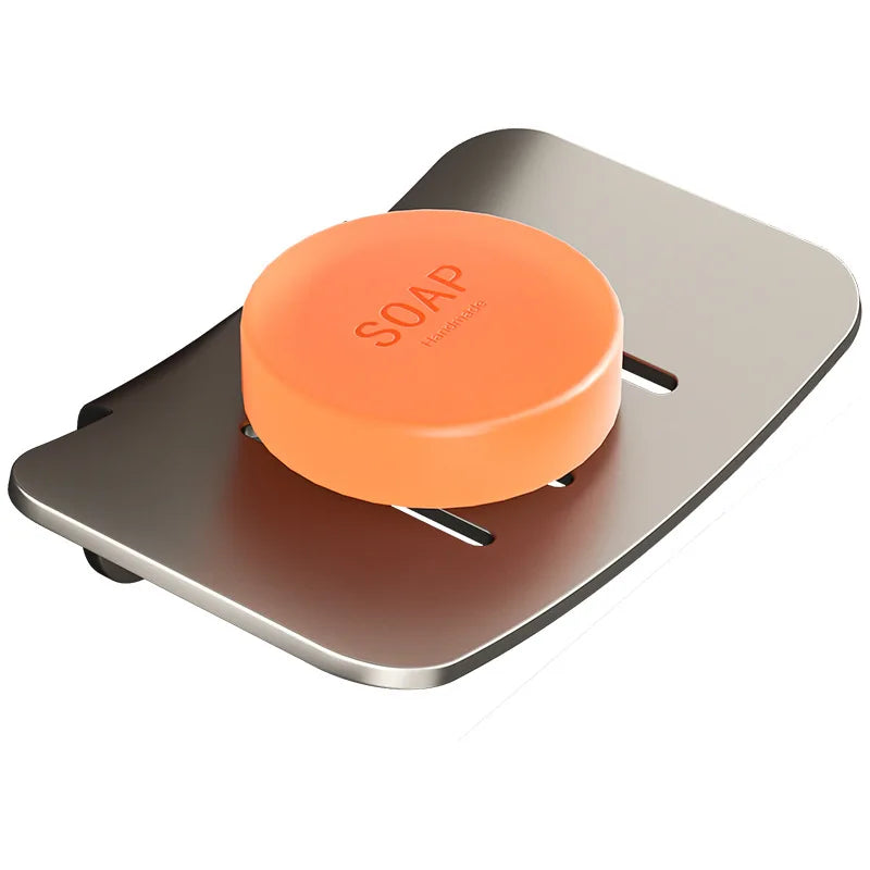 An orange wall-mounted soap dish made of aluminum with a drain, shown from above.