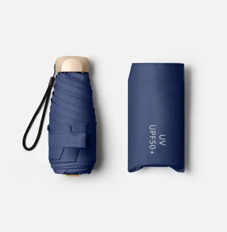 A dark blue pocket-size folding umbrella with a light-colored handle and UV protection text on the sleeve.