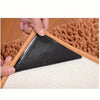 A black non-slip rug pad gripper is shown being placed onto a light-colored rug or floor surface.