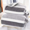 A stack of gray and white striped microfiber bath towels folded neatly on a white surface.