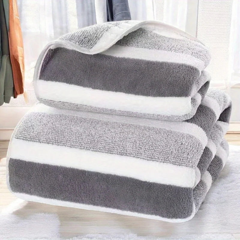 A stack of gray and white striped microfiber bath towels folded neatly on a white surface.