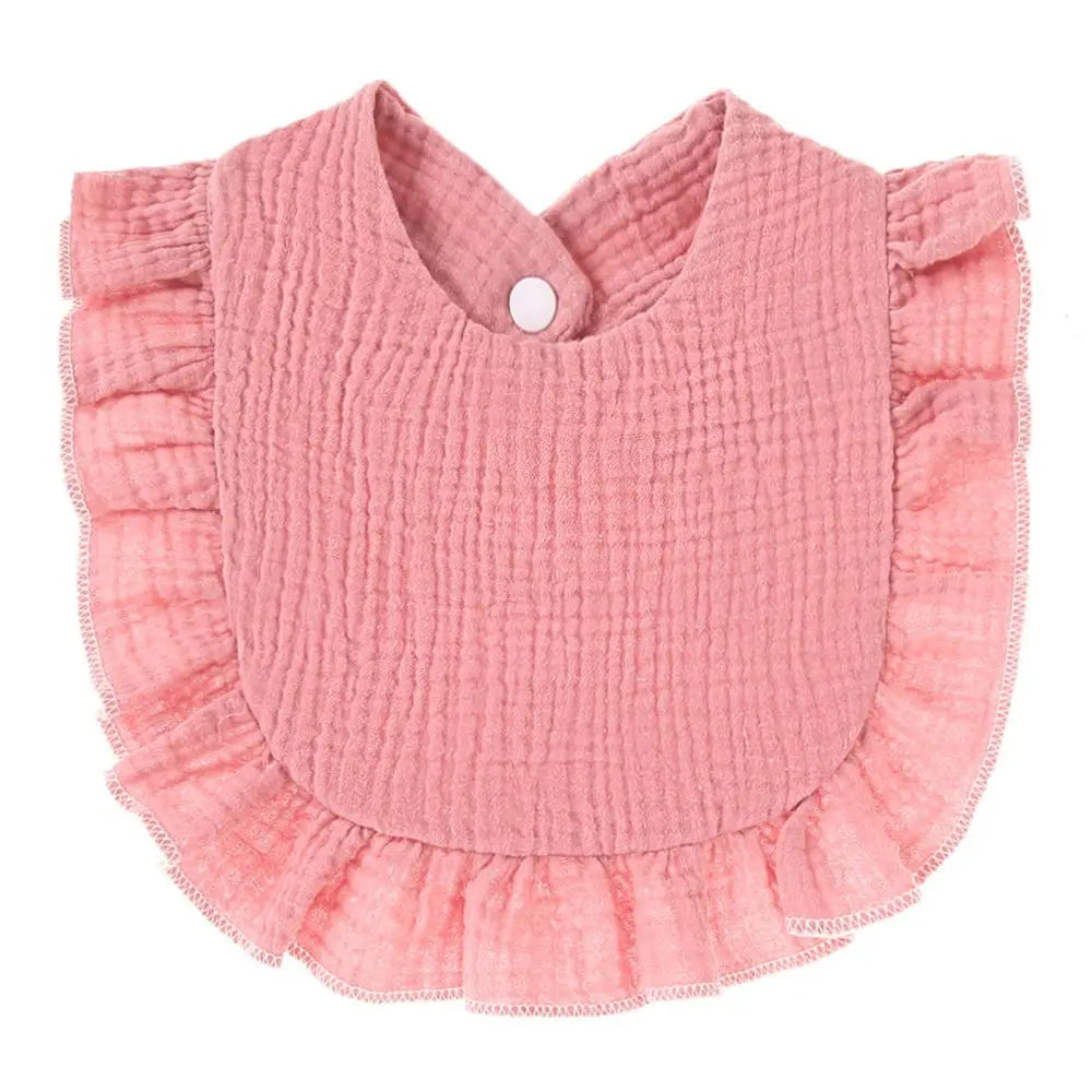 A pink, textured cotton baby bib in a bandana style with ruffled edges and a button closure.