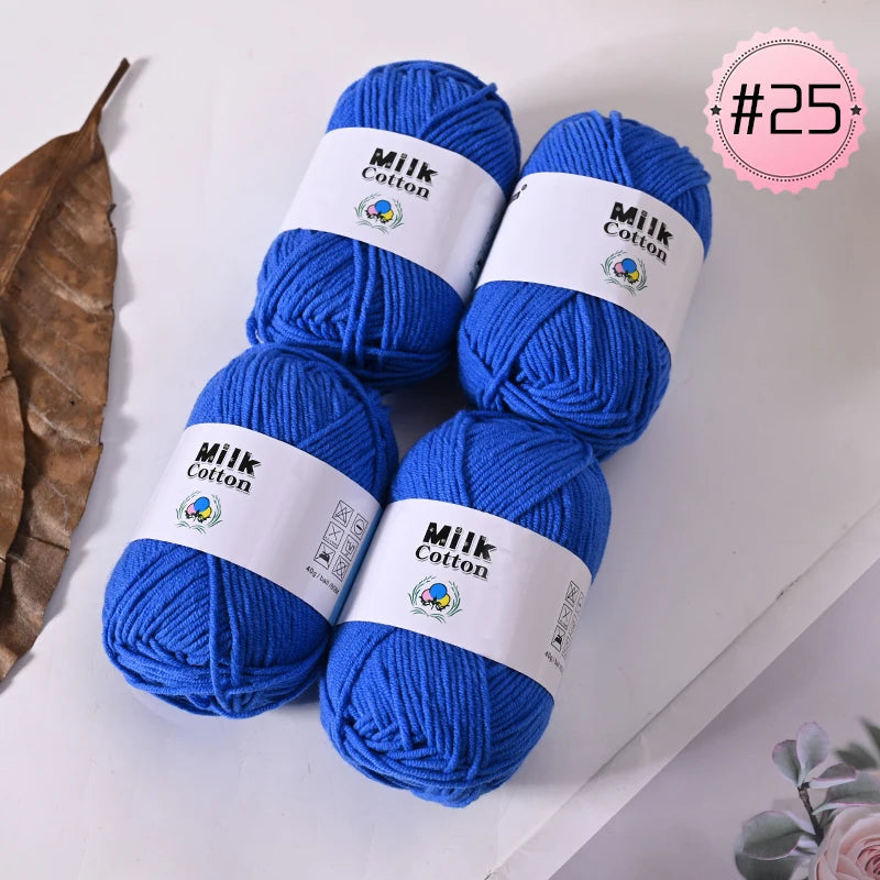 A stack of bright blue Milk Cotton yarn skeins with white labels and a pink circle marked #25.