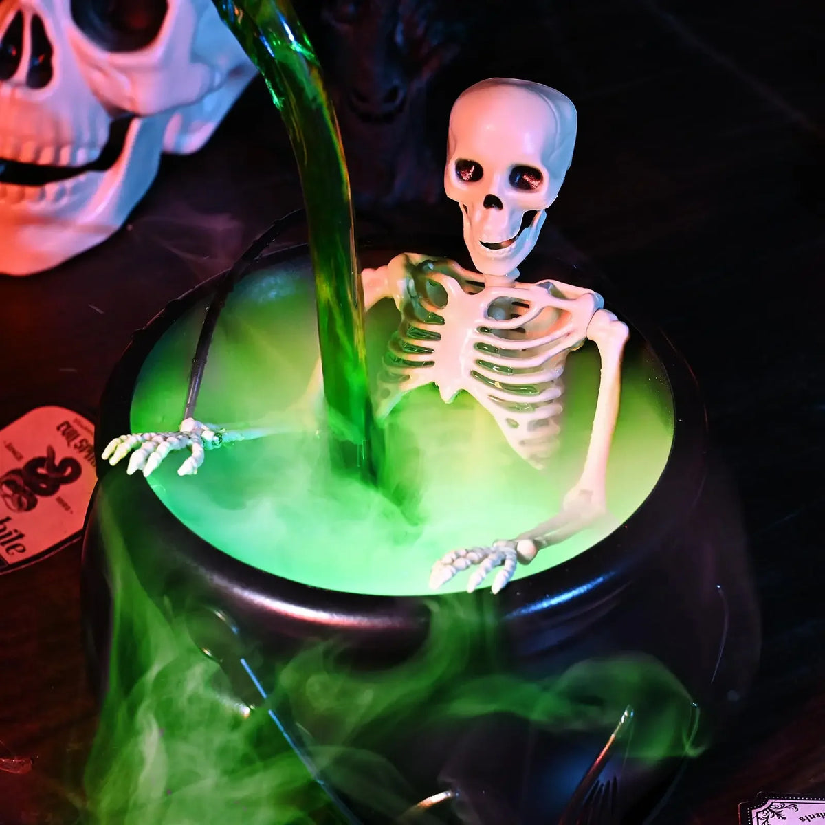 A black cauldron filled with glowing green liquid and a white skull skeleton figure emerging from the potion.