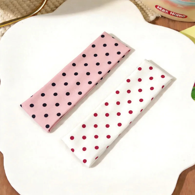 Tire-l'oreille à pois rose et blanc posé sur une surface blanche.