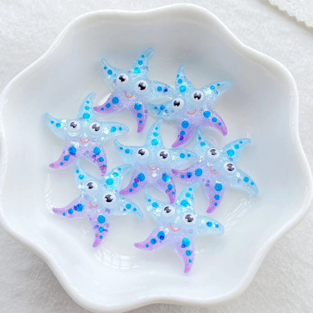 A collection of small, iridescent blue and purple starfish resin charms on a white dish.