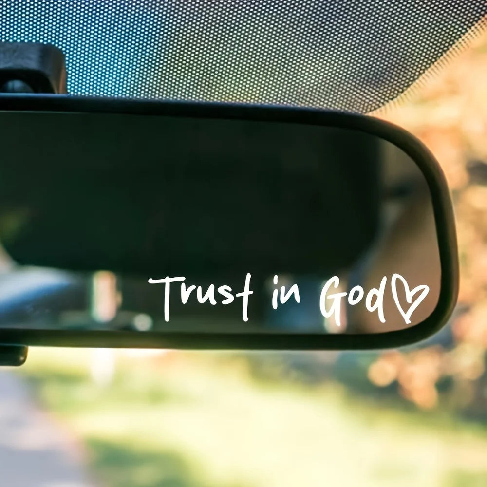 A close-up shot of a black rearview mirror showing the white text Trust in God with a heart symbol.