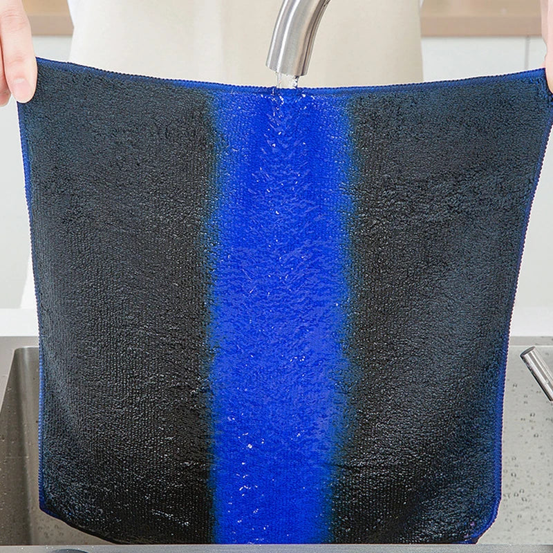 A black microfiber cleaning towel with a vertical blue stripe being rinsed under a faucet.